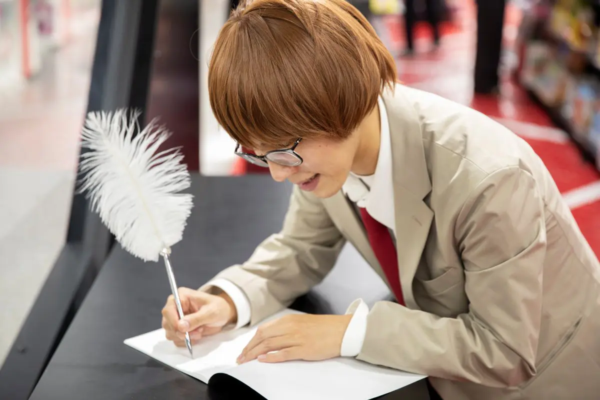 羽ペンでKUJI NOTEになにか書いているたかやさん